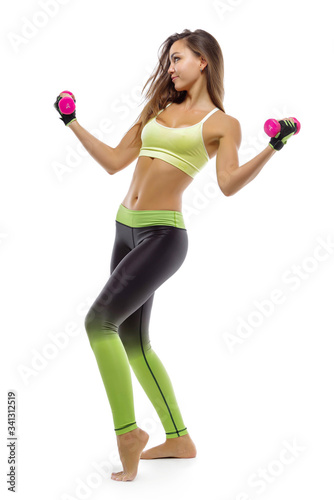 A young girl poses in sportswear on a white background, with dumbbells