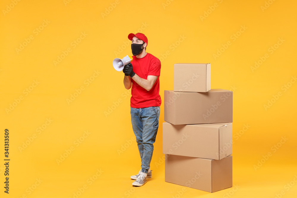 Delivery man employee in red cap blank t-shirt uniform face mask glove hold empty cardboard box isolated on yellow background studio Service quarantine pandemic coronavirus flu virus 2019-ncov concept Delivery man employee in red cap blank t-shirt uniform face mask glove hold empty cardboard box isolated on yellow background studio Service quarantine pandemic coronavirus flu virus 2019-ncov concept