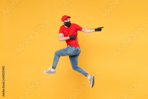 Fun jumping delivery man in red cap t-shirt uniform sterile face mask gloves isolated on yellow background studio Guy employee courier Service quarantine pandemic coronavirus virus 2019-ncov concept.