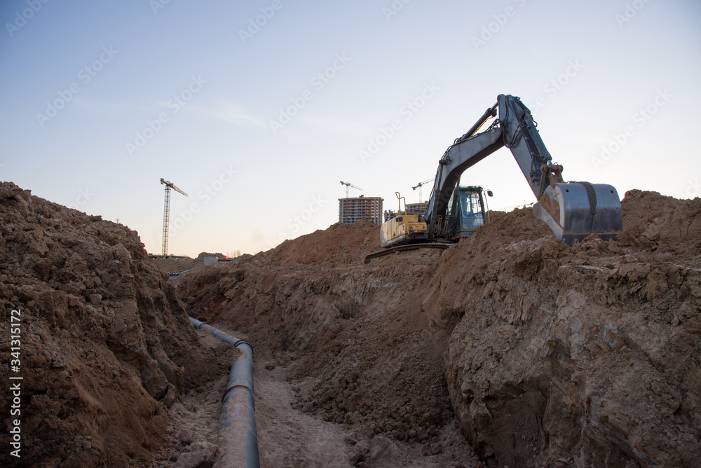 Excavator at work trenching at a construction site. Trench for laying
