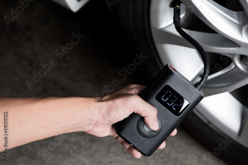 Hand of man holding digital gauge checking tire pressure 32 psi measurement