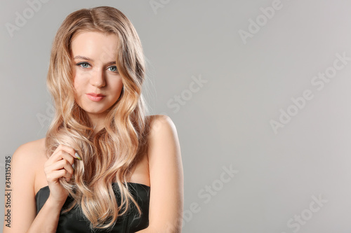 Young blonde with beautiful hair on grey background
