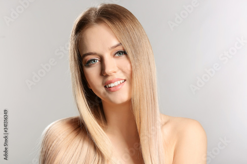 Young blonde with beautiful hair on grey background