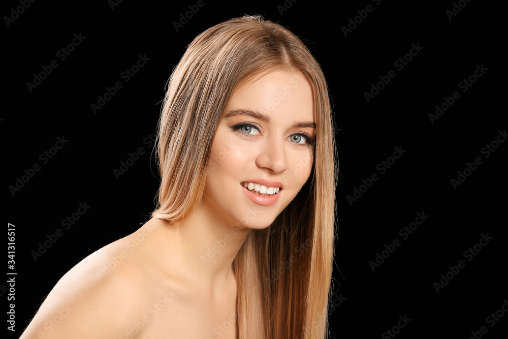 Fototapeta premium Young blonde with beautiful hair on dark background