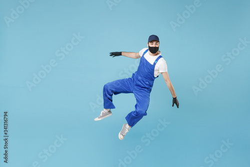 Fun jumping delivery man in cap t-shirt uniform sterile face mask glove isolated on blue background studio Guy employee courier Service quarantine pandemic coronavirus virus covid-19 2019-ncov concept