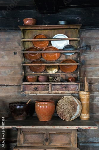a cupboard for dishes in an old rural house, earthenware, large plates, cast iron