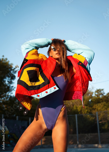 Woman In Summer. Fashion Sexy Model in Swimsuit and colourful coat at basketball playground.Sexy woman in purple swimsuit