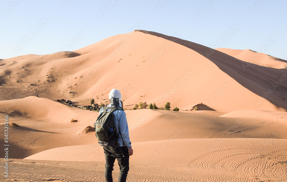 Joven viajero con mochila y turbante contemplando el desierto