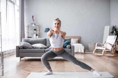 Sporty young woman doing exercise alone in living room.