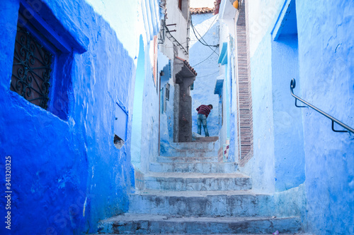 Calle estrecha con escalones y paredes azules en Chefchauen y un hombre al fondo © Javi Sánchez