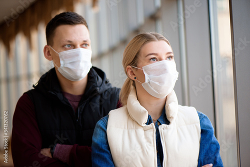 Ill man and woman feeling sick, wearing protective mask against transmissible infectious diseases and as protection against the flu.