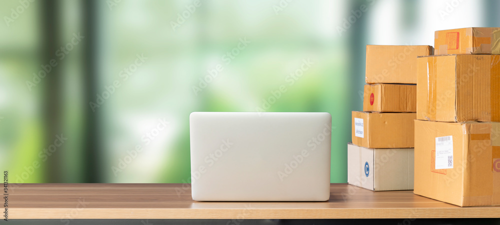 Laptop computer at workplace of start up, small business owner. cardboard parcel box of product for deliver to customer. Online selling, e-commerce, packing concept, work from home Laptop computer at workplace of start up, small business owner. cardboard parcel box of product for deliver to customer. Online selling, e-commerce, packing concept, work from home