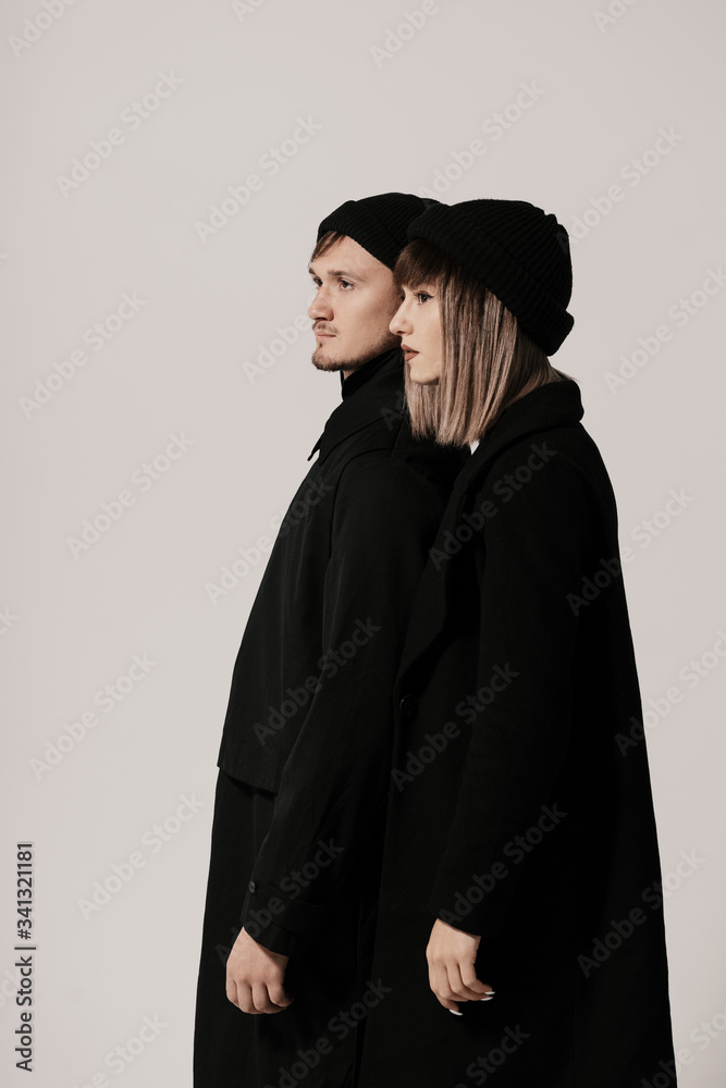 Portrait of urban fashion beautiful couple in black clothes posing over white background together. Close up fashion portrait of stylish young couple pretty woman and handsome man