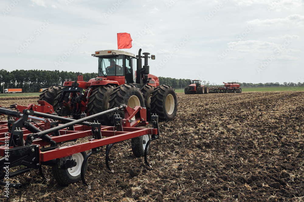 Obraz premium large red tractor trailer for tillage during sowing in spring in Russia