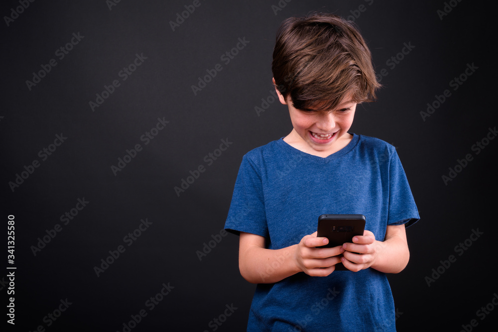 Portrait of happy young handsome boy using phone