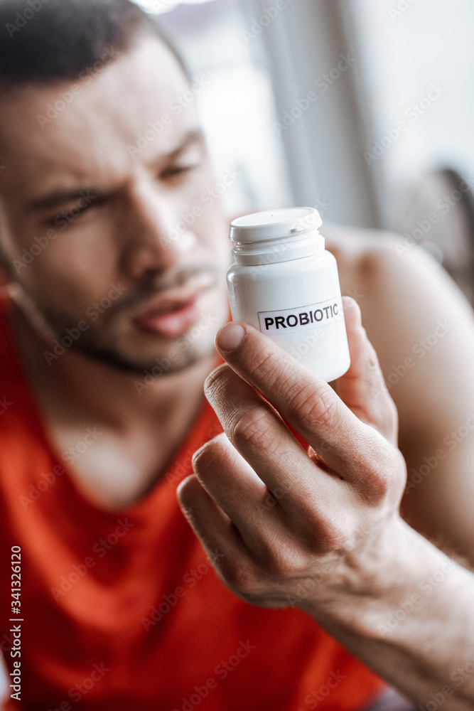 selective focus of sportsman holding bottle with probiotic lettering in gym selective focus of sportsman holding bottle with probiotic lettering in gym