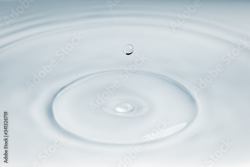 Small droplet of water falling over some ripple effect on the surface of water