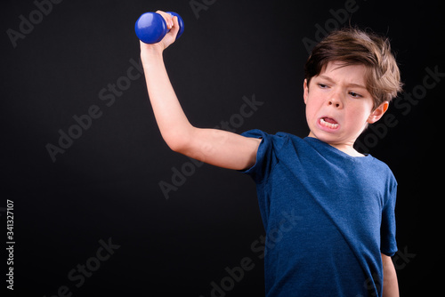 Portrait of funny young boy exercising with dumbbells