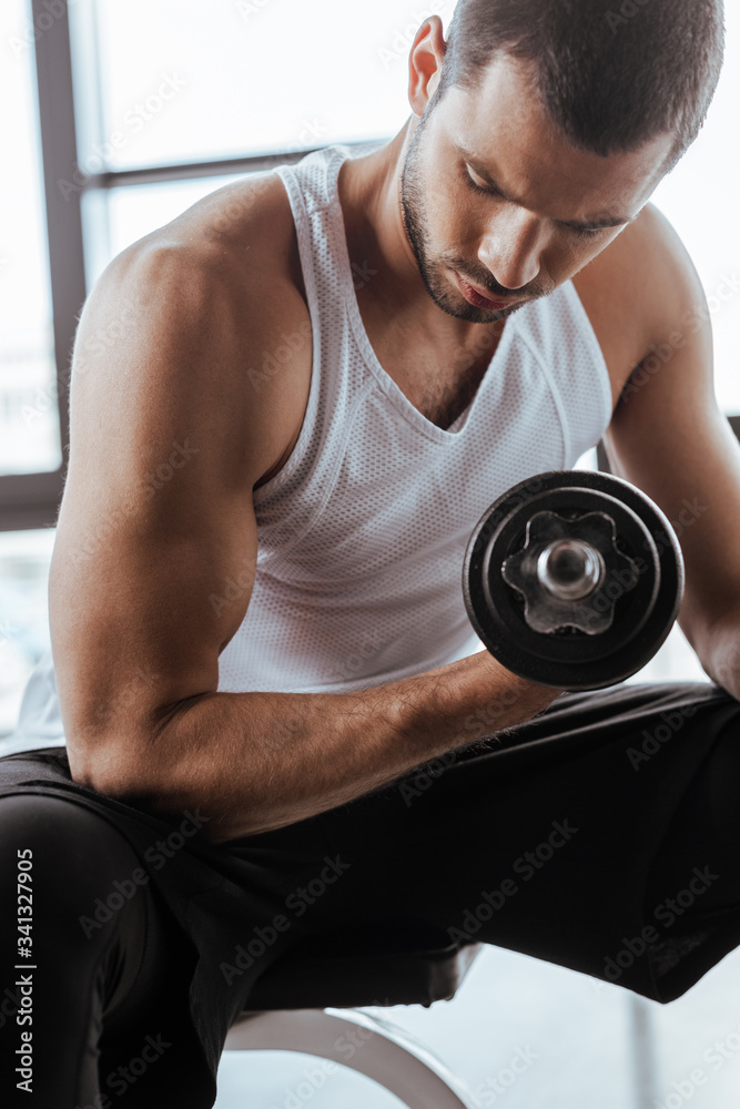 handsome sportsman exercising with dumbbell in gym handsome sportsman exercising with dumbbell in gym