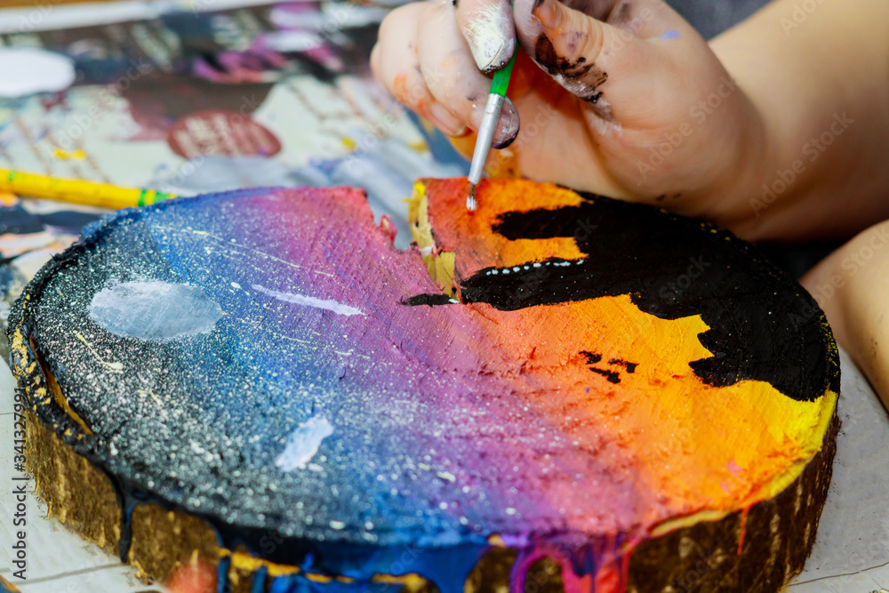 Obraz premium Girl uses colored paints brushes a picture in wooden