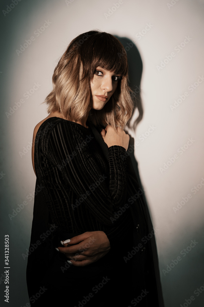 Naklejka premium Portrait beautiful woman with attitude wearing black clothes posing while looking at camera with shadow in the background