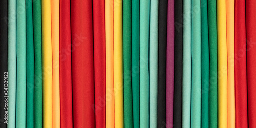 Background from colored cotton clothes. Colors of rainbow. Colored vertical strips of fabric. Banner