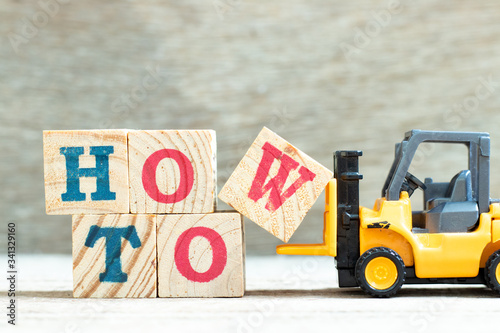 Fotografie Toy forklift hold letter block w to complete word how to on wood background