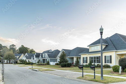 A street view of a new construction neighborhood with larger landscaped homes and houses with yards and sidewalks taken near sunset with copy space photo