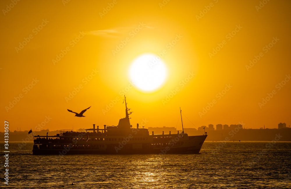 Ferry sails through the Bosphorus Strait in Istanbul, Turkey, during sunset
