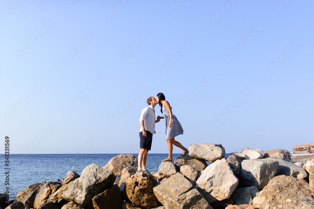 Young beautiful couple kissing on sea background.