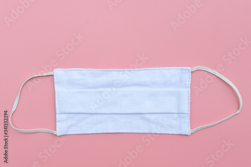 White fabric cloth face mask for protective on pink background. for cover the mouth and nose for safety outdoor activity,illness or Air pollution Healthcare and medical concept