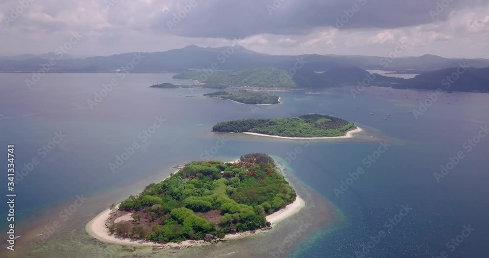 A top drone shot of island set with white sand beaches and green trees A top drone shot of island set with white sand beaches and green trees