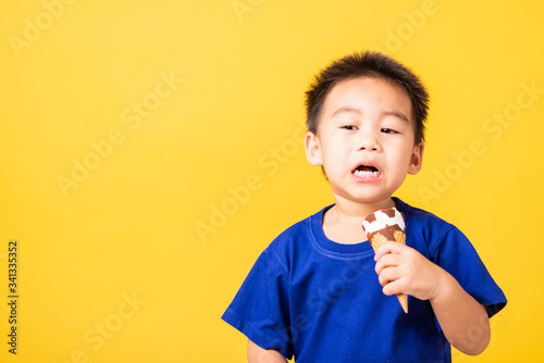 kid cute little boy attractive laugh smile playing holds and eating sweet chocolate ice cream waffle cone