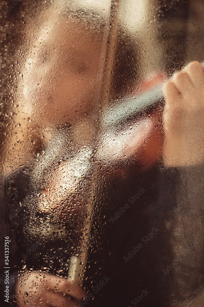 Girl with a violin behind a glass window with drops of water, low key. Music concept