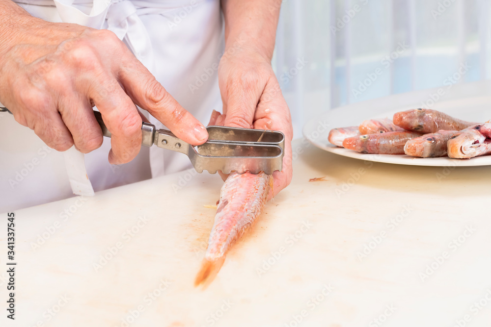 hands of woman flaking a fresh red mullet