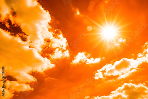 Hot summer or heat wave background, orange sky with glowing sun and clouds photo