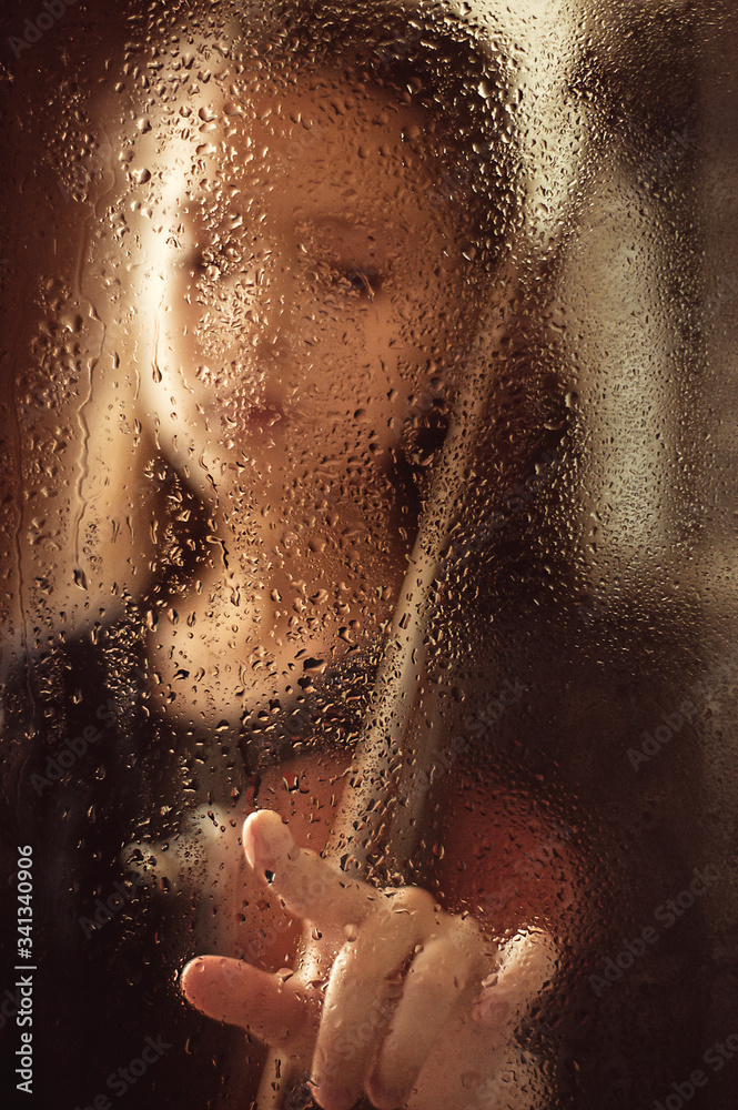 Girl with a violin behind a glass window with drops of water, low key. Music concept