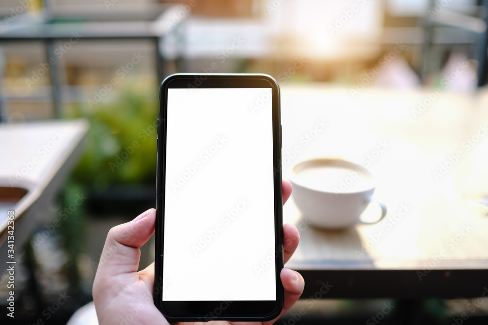 Mockup image of a woman holding and showing black mobile phone with blank screen in cafe. Mockup image of a woman holding and showing black mobile phone with blank screen in cafe.