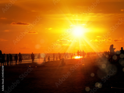 group of silhouetted people on public beach over orange colored sunset sky in Siesta key, Sarasota, Florida © jokerpro