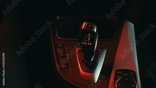 the man in the car puts hand the gear selector into drive mode