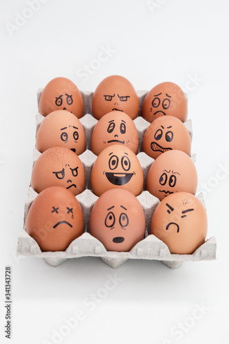 Don't worry be happy. egg in the middle of a group of angry, envious, crying eggs. Idea of positive approach. White background.