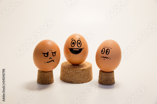 Fotografie Egg with face standing in the middle of venvious and angry eggs