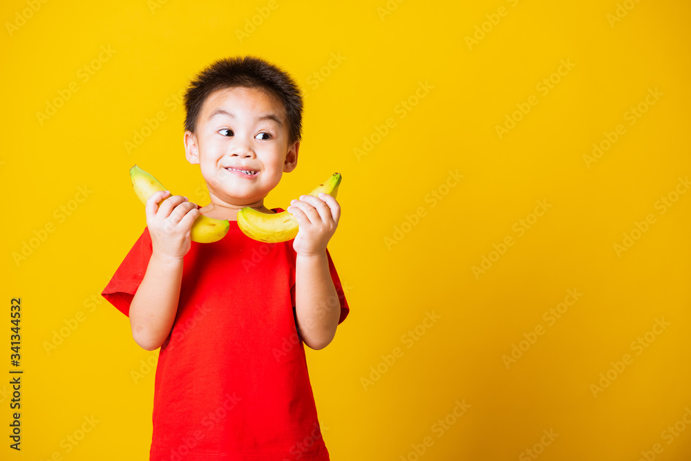 child or kid cute little boy attractive smile playing holds banana fruit