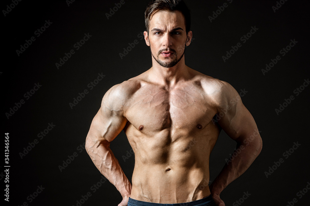 Fototapeta premium Portrait of an attractive muscular man on a dark background