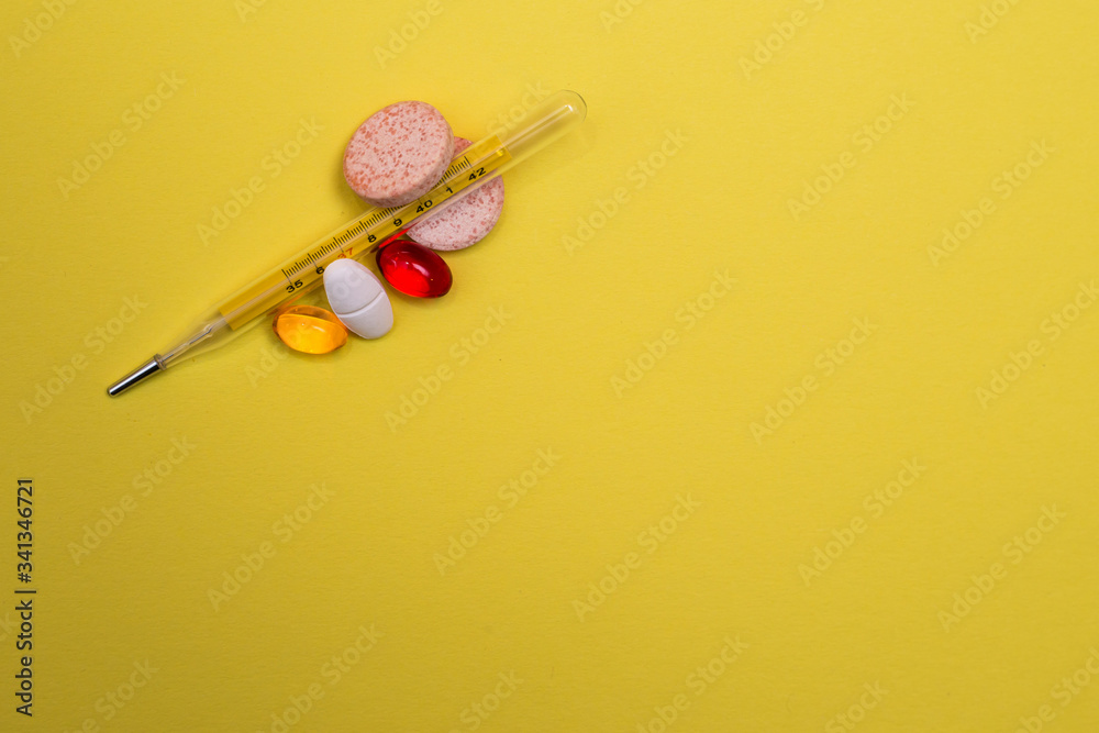 Assorted medicine pills, pharmaceutical vitamin C and thermometer on yellow background 2 Assorted medicine pills, pharmaceutical vitamin C and thermometer on yellow background 2
