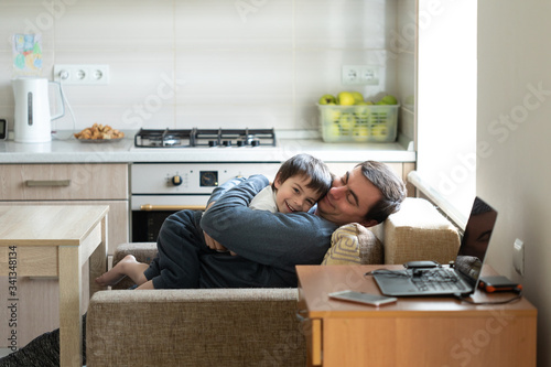 Father hugging his son sitting in armchair at home