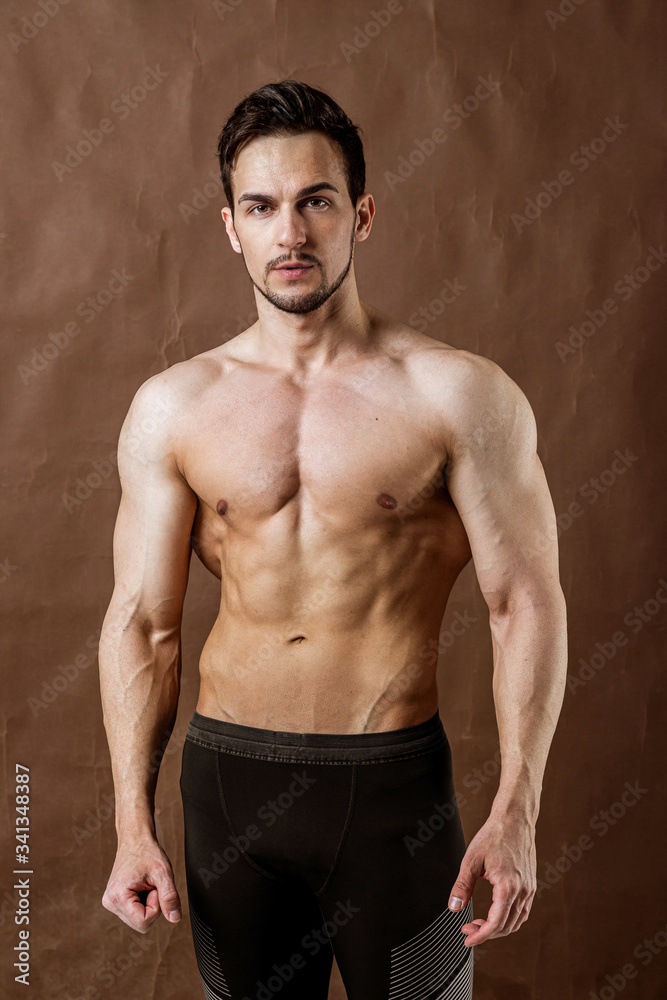 Handsome sportsman bodybuilder posing on brown craft background