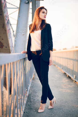 Model posing in trousers and a jacket on the bridge.