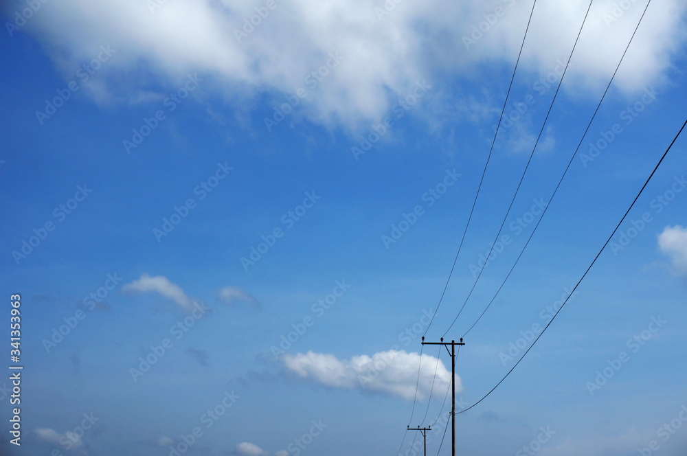 Pylon of a power line with outgoing electric wires againts a cloud blue sky Pylon of a power line with outgoing electric wires againts a cloud blue sky