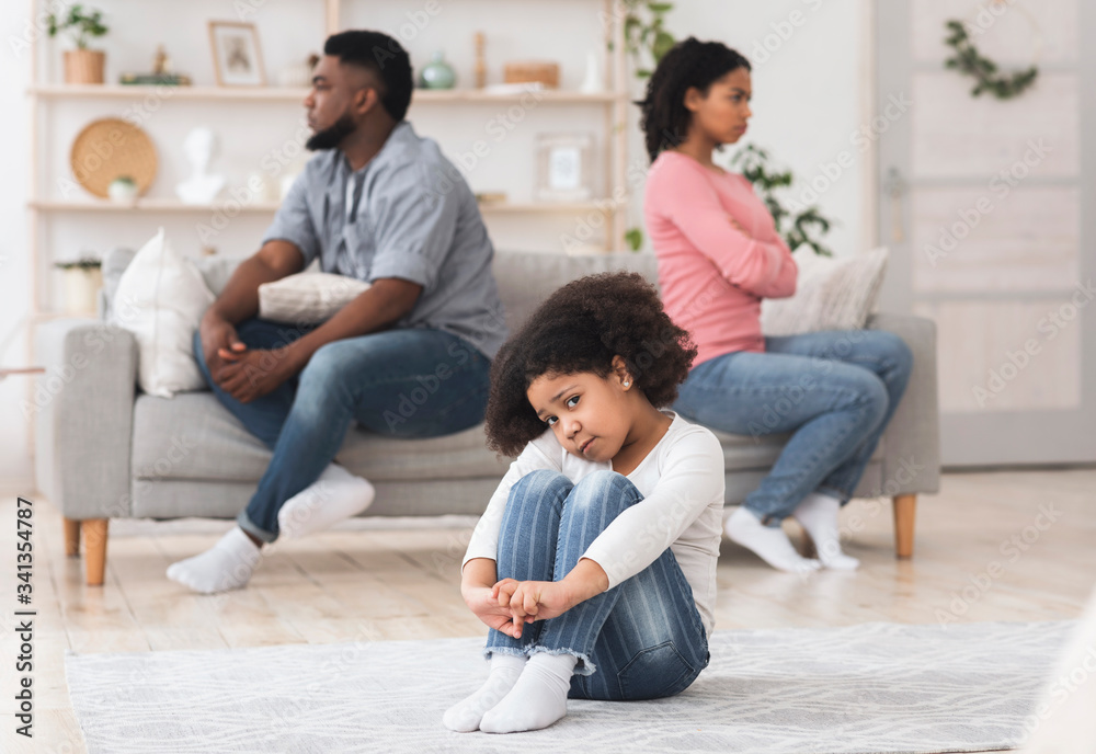 Upset little african girl sitting alone tired of parents quarrels Upset little african girl sitting alone tired of parents quarrels